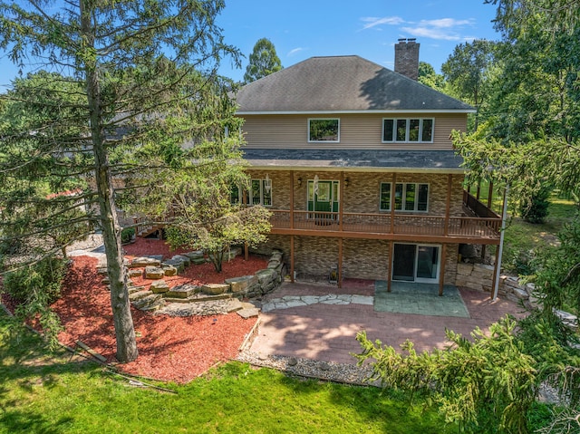 back of property featuring a shingled roof, a patio area, a lawn, and a chimney