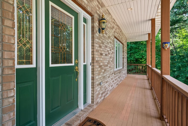 view of exterior entry featuring a porch and brick siding