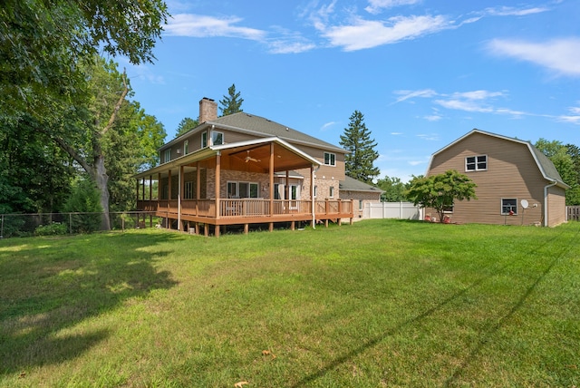 rear view of property featuring a chimney, a lawn, stone siding, a fenced backyard, and a wooden deck