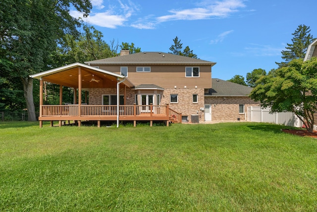 back of property with ceiling fan, fence, a deck, and a lawn