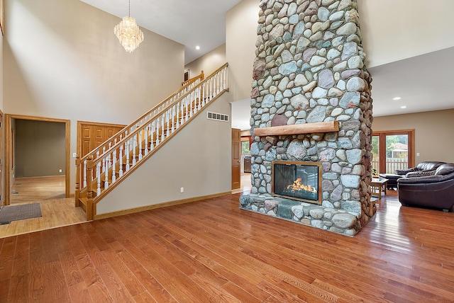 living room featuring a fireplace, visible vents, a high ceiling, wood finished floors, and stairs