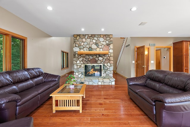 living area featuring a stone fireplace, wood finished floors, visible vents, and recessed lighting