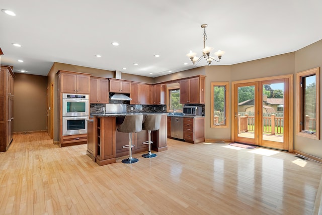 kitchen with brown cabinets, stainless steel appliances, tasteful backsplash, a kitchen island, and a kitchen breakfast bar