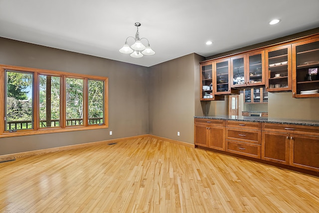 bar with light wood-style flooring, recessed lighting, baseboards, decorative light fixtures, and an inviting chandelier