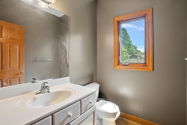 bathroom featuring toilet, vanity, and baseboards