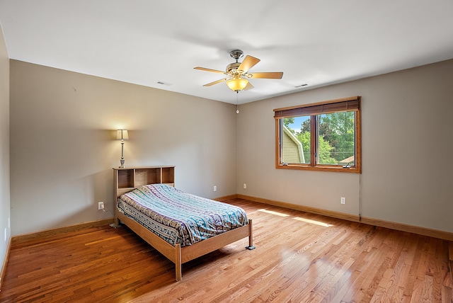 bedroom featuring light wood finished floors, baseboards, visible vents, and ceiling fan