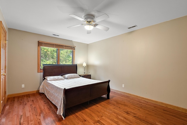 bedroom with baseboards, ceiling fan, visible vents, and wood finished floors