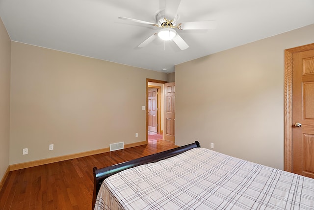 unfurnished bedroom featuring a ceiling fan, visible vents, baseboards, and wood finished floors