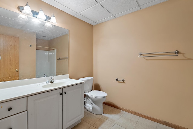 full bath with a drop ceiling, tile patterned flooring, toilet, vanity, and walk in shower