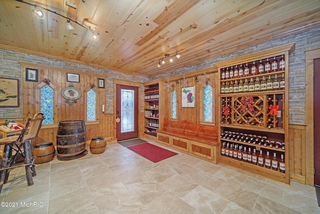 wine room with wood ceiling, wood walls, and light tile floors