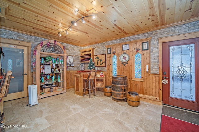 tiled entrance foyer featuring wooden ceiling, wood walls, and track lighting