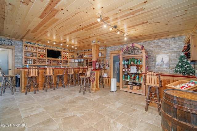 tiled dining area with wood ceiling, track lighting, and indoor bar