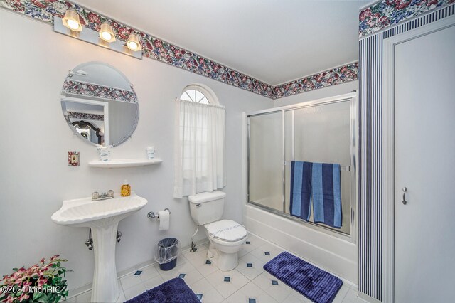 bathroom with toilet, combined bath / shower with glass door, and tile flooring