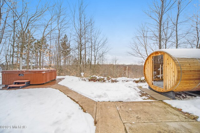 snowy yard with a hot tub and an outdoor structure