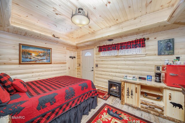 bedroom featuring light hardwood / wood-style flooring, a wood stove, and wood ceiling