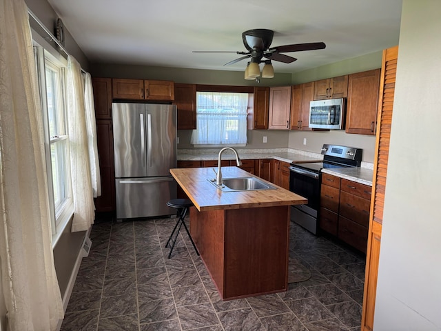 kitchen featuring stainless steel appliances, sink, a center island with sink, and plenty of natural light