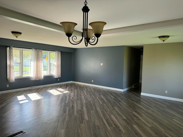 spare room with dark wood-type flooring and a notable chandelier