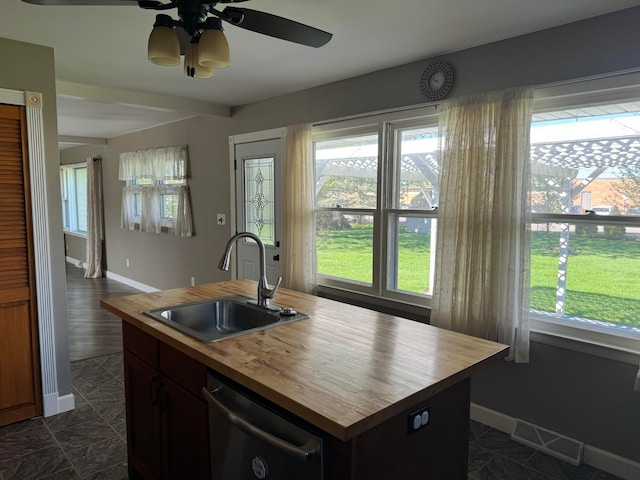 kitchen featuring dishwashing machine, butcher block countertops, sink, ceiling fan, and an island with sink