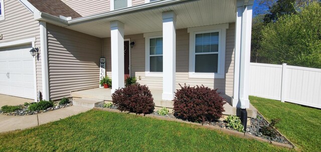 doorway to property featuring a garage, covered porch, and a yard