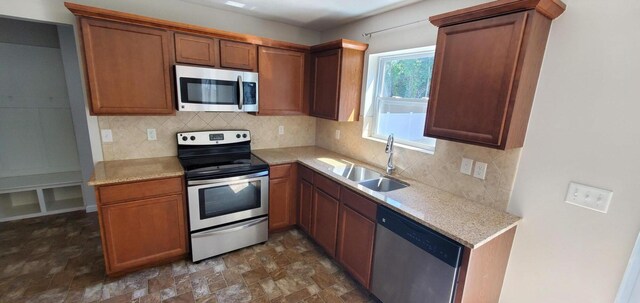 kitchen featuring appliances with stainless steel finishes, dark tile patterned floors, tasteful backsplash, and sink