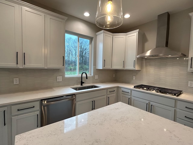 kitchen with decorative backsplash, appliances with stainless steel finishes, wall chimney exhaust hood, sink, and white cabinets