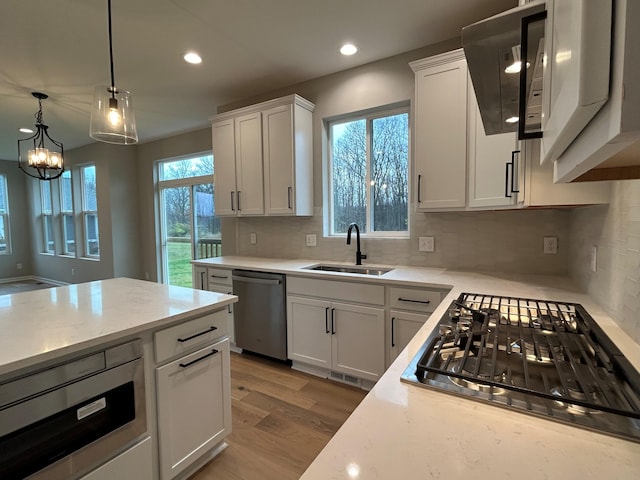 kitchen with white cabinets, sink, light hardwood / wood-style flooring, appliances with stainless steel finishes, and tasteful backsplash