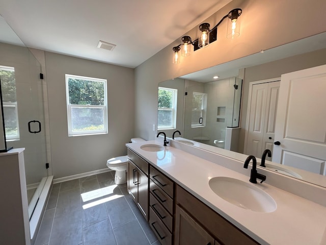 bathroom with plenty of natural light, toilet, a shower with shower door, and vanity