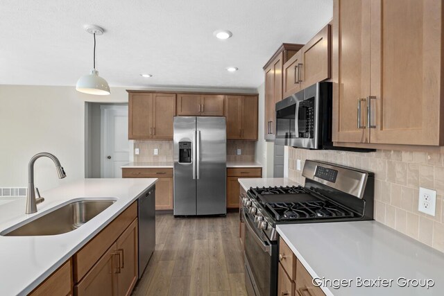 kitchen featuring sink, dark hardwood / wood-style flooring, decorative backsplash, hanging light fixtures, and stainless steel appliances