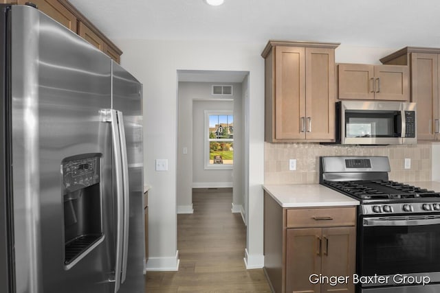 kitchen with tasteful backsplash, stainless steel appliances, and dark wood-type flooring