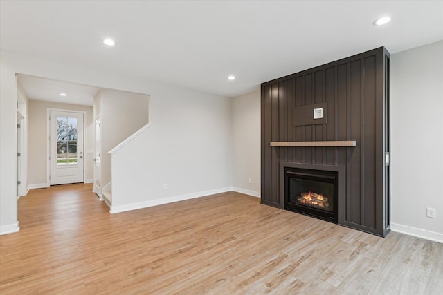 unfurnished living room with a large fireplace and light hardwood / wood-style flooring