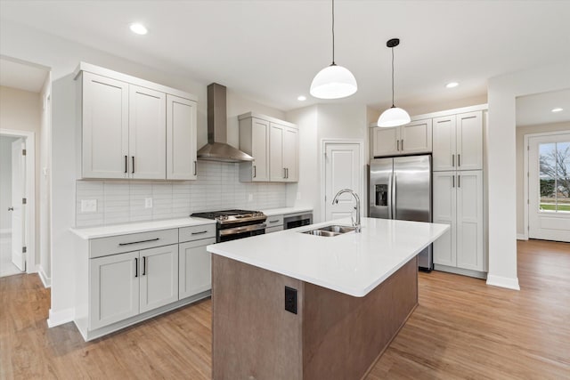 kitchen with tasteful backsplash, pendant lighting, sink, appliances with stainless steel finishes, and wall chimney exhaust hood