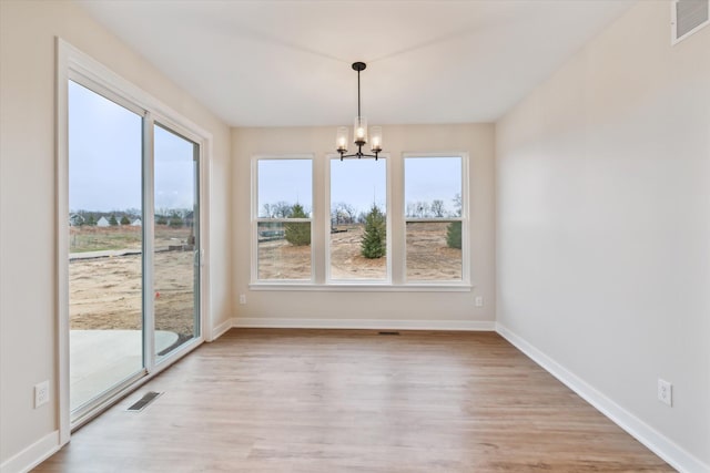 unfurnished dining area featuring light wood-type flooring and a notable chandelier