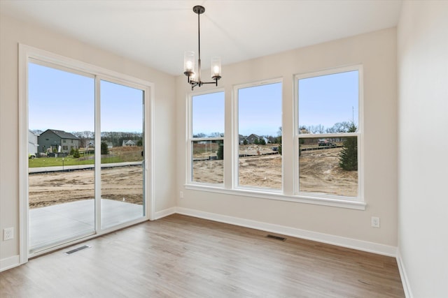 unfurnished dining area with hardwood / wood-style floors and an inviting chandelier