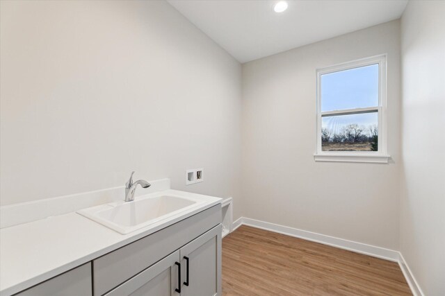 laundry room featuring cabinets, sink, washer hookup, and light hardwood / wood-style floors