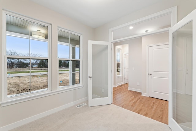 carpeted spare room featuring french doors