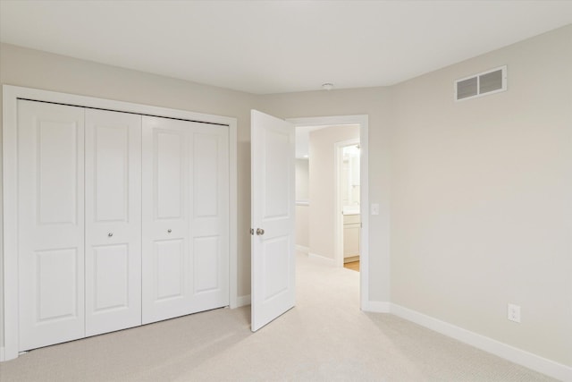 unfurnished bedroom featuring light colored carpet and a closet