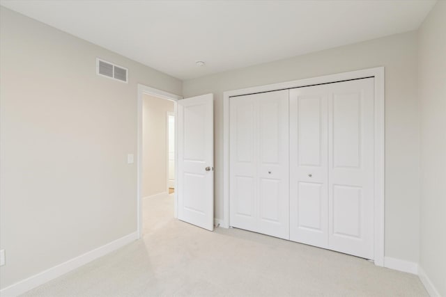 unfurnished bedroom with light carpet and a closet