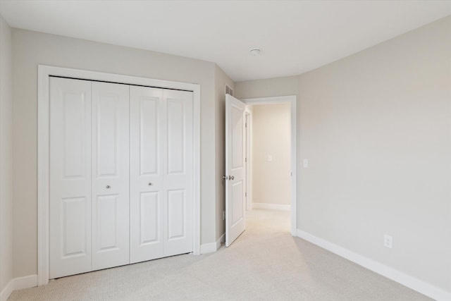 unfurnished bedroom with light colored carpet and a closet