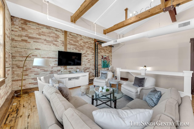 living room with hardwood / wood-style flooring, high vaulted ceiling, beamed ceiling, and brick wall