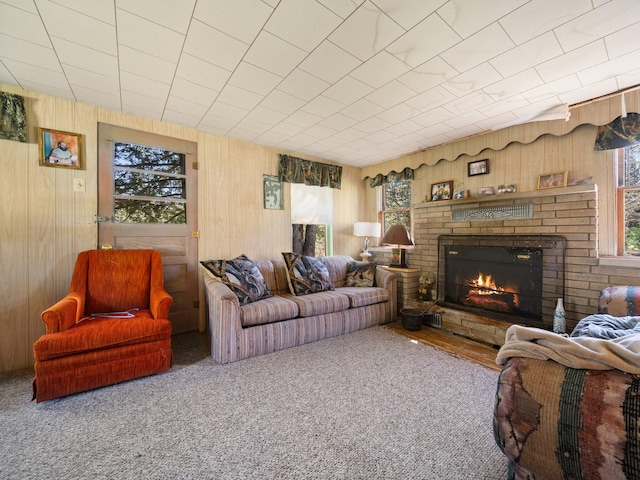 carpeted living room featuring wood walls and a fireplace