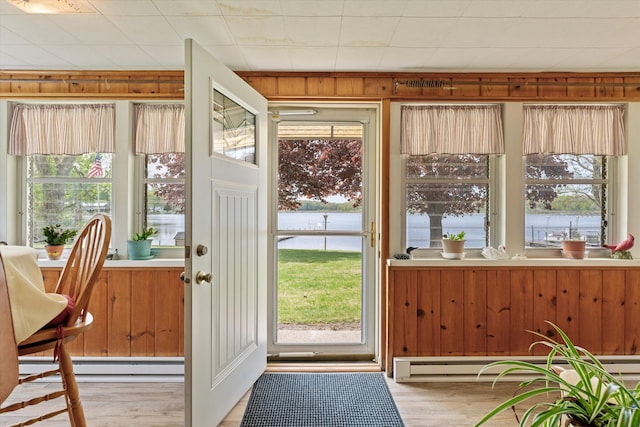 doorway to outside featuring wooden walls, a baseboard heating unit, and wood-type flooring