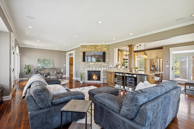 living room with ornamental molding, wine cooler, a stone fireplace, and dark hardwood / wood-style floors