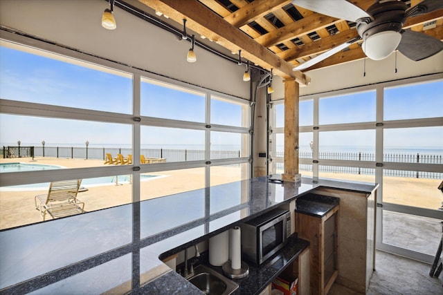 sunroom with a water view and ceiling fan