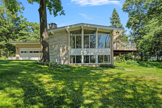 exterior space featuring a garage, a sunroom, and a lawn