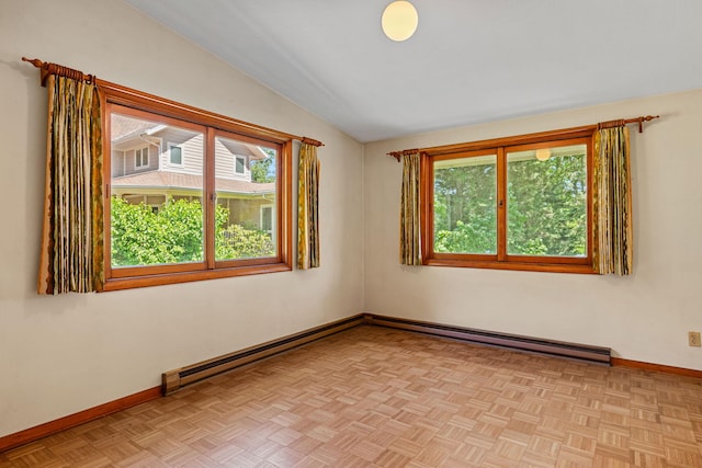 empty room featuring a baseboard radiator, vaulted ceiling, light parquet floors, and a wealth of natural light