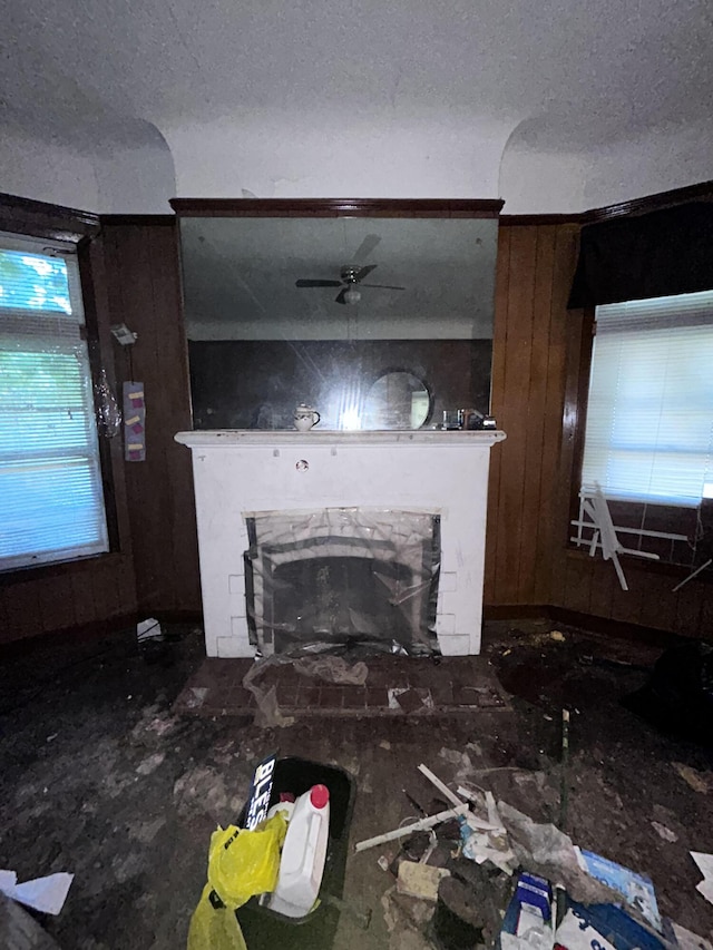 unfurnished living room with a stone fireplace and wooden walls