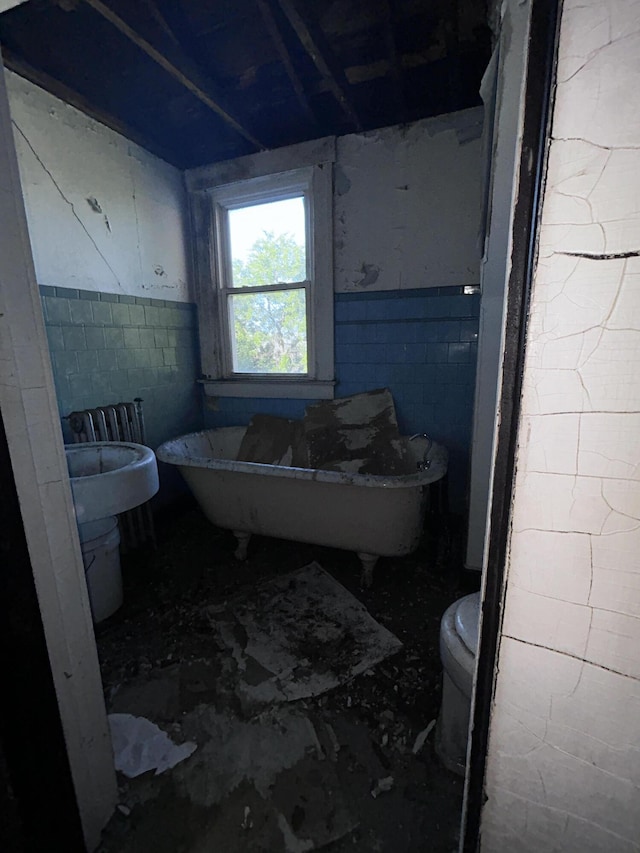 bathroom with tile walls, a bath, and toilet