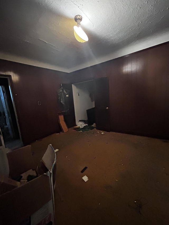 bedroom with wooden walls and a textured ceiling