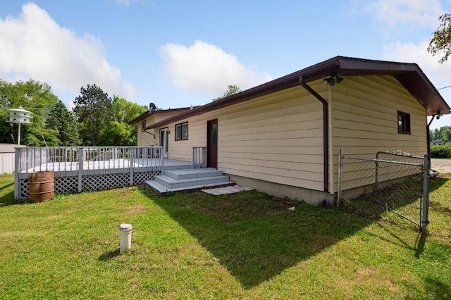 back of house featuring a lawn and a wooden deck