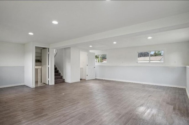 basement featuring a wealth of natural light and dark hardwood / wood-style flooring